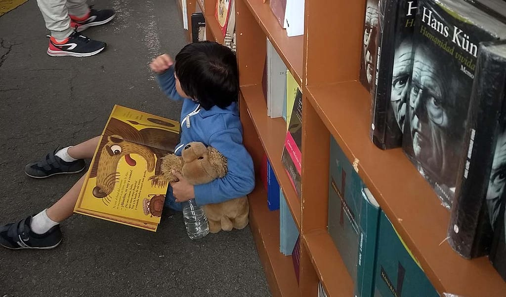 niño leyendo en el piso de un stad de una feria del libro
